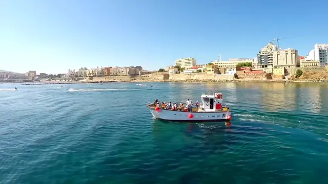 Vista de Ceuta desde la bahía sur, con una embarcación de recreo en primer plano y el frente marítimo al fondo.