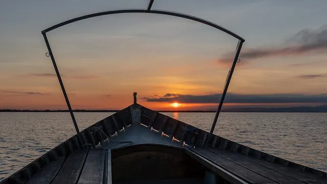 Atardecer sobre la Albufera de Valencia visto desde la proa de una barca tradicional.